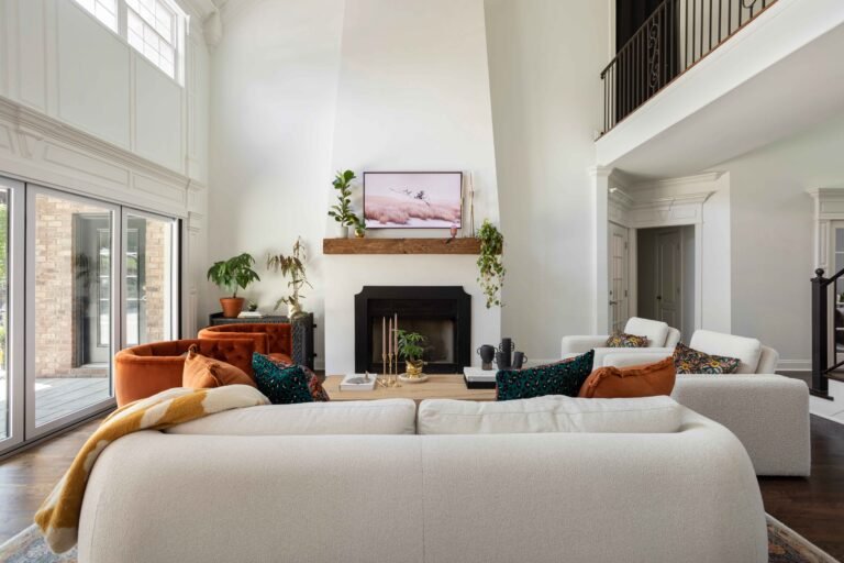 A modern living room with a white fireplace large windows and a cozy seating area remodel by AMI Build 768x512